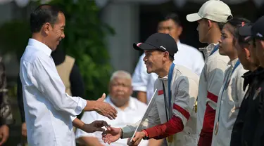 Presiden Joko Widodo menyalami peraih medali emas Indonesia di cabang olahraga panjat tebing Olimpiade Paris 2024, Veddriq Leonardo saat upacara penerimaan yang dilakukan di Istana Merdeka, Jakarta, pada Kamis 15 Agustus 2024. (BAY ISMOYO/AFP)