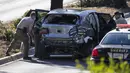Deputi Sheriff County Los Angeles mengumpulkan bukti dari mobil pegolf Tiger Woods setelah kecelakaan di Rolling Hills Estates, California, Selasa (23/2/2021). Sumber di dalam Kepolisian LA mengatakan tak ditemukan barang-barang ilegal di dalam mobil Woods. (David McNew/Getty Images/AFP)