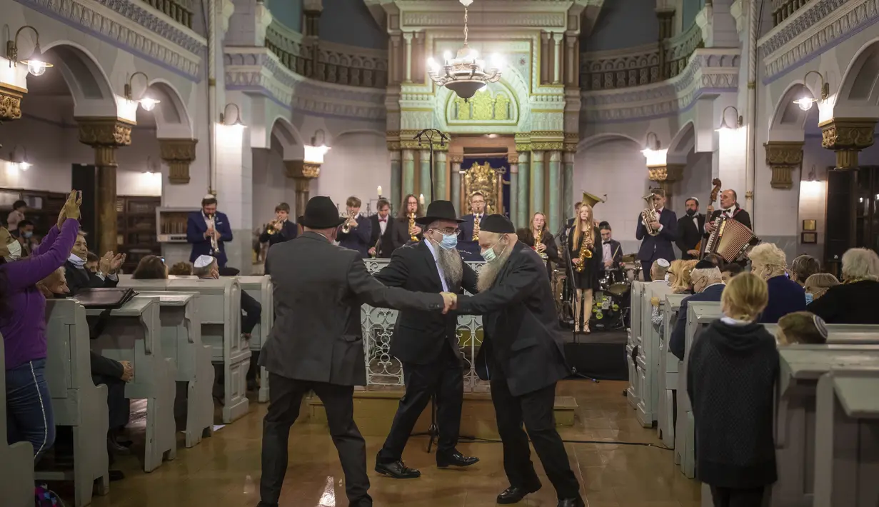 Pria menari selama hari libur Yahudi Hanukkah di Sinagoga di Vilnius, Lithuania, Minggu (28/11/2021). Perayaan tahunan komunitas malam pertama Hanukkah kembali dengan kapasitas penuh tahun ini setelah perayaan dibatasi pada tahun 2020 karena pandemi virus corona. (AP Photo/Mindaugas Kulbis)