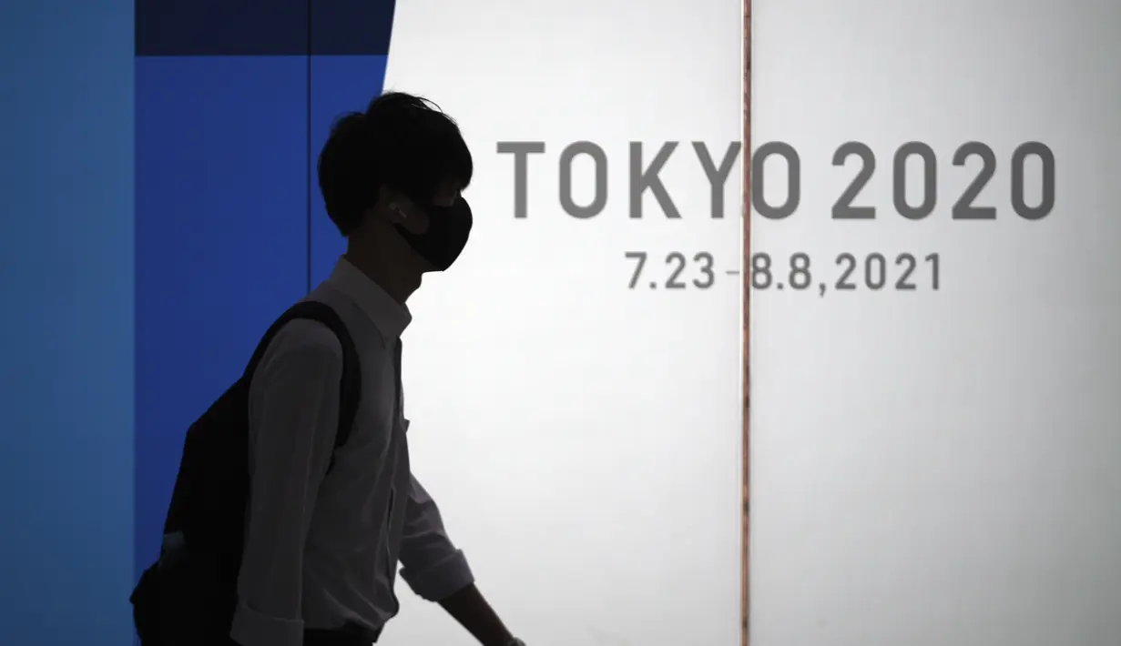 Seorang pria yang mengenakan masker pelindung untuk membantu mengekang penyebaran virus corona berjalan di depan logo Olimpiade Tokyo 2020 di Tokyo, Selasa (22/6/2021). Ibu kota Jepang mengkonfirmasi lebih dari 430 kasus virus corona baru pada hari Selasa. (AP Photo/Eugene Hoshiko)