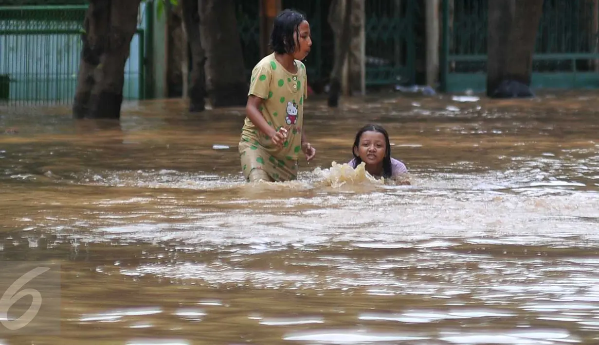 Dua anak bermain banjir di kawasan Tebet, Jakarta, Selasa (8/3/2016). Kawasan Tebet terendam banjir akibat meluapnya Sungai Ciliwung. (Liputan6.com/Gempur M Surya) 
