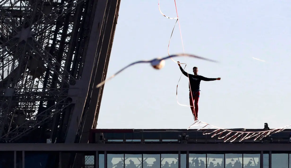 Seniman trapeze, Nathan Paulin berjalan di seutas tali dari Menara Eiffel menuju alun-alun Trocadero, Paris, 9 Desember 2017. Aksi itu bagian dari Telethon ke-31 untuk menggalang dana bagi kegiatan penelitian penyakit langka. (JACQUES DEMARTHON/AFP)