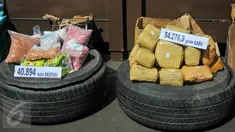 Petugas memperlihatkan barang bukti sabu dan pil ekstasi yang berhasil diamankan oleh BNN, Jakarta, Jumat (13/5). 54 kg sabu dan 40 ribu butir pil ekstasi yang disita dari jaringan internasional itu disimpan di ban serep mobil. (Liputan6.com/Yoppy Renato)