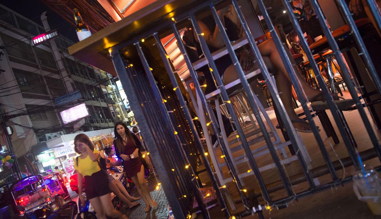 Foto pada 11 Oktober 2018 memperlihatkan wanita berjalan melewati sebuah bar di Nana Red Light Distrik, Bangkok, Thailand. Kawasan tersebut merupakan tempat lokalisasi hiburan malam paling tersohor di Bangkok. (Romeo GACAD / AFP)