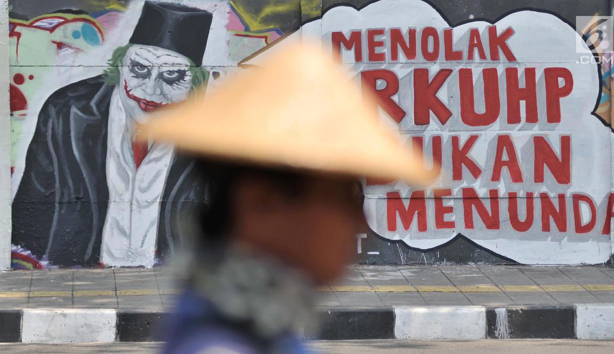 Mural bertulis 'Menolak RKUHP Bukan Menunda' terpampang pada dinding di Jalan Pemuda, Rawamangun, Jakarta, Selasa (1/10/2019). Mural tersebut respons dari seniman Jakarta terhadap RUU KUHP yang dinilai mencederai tatanan demokrasi. (merdeka.com/Iqbal Nugroho)