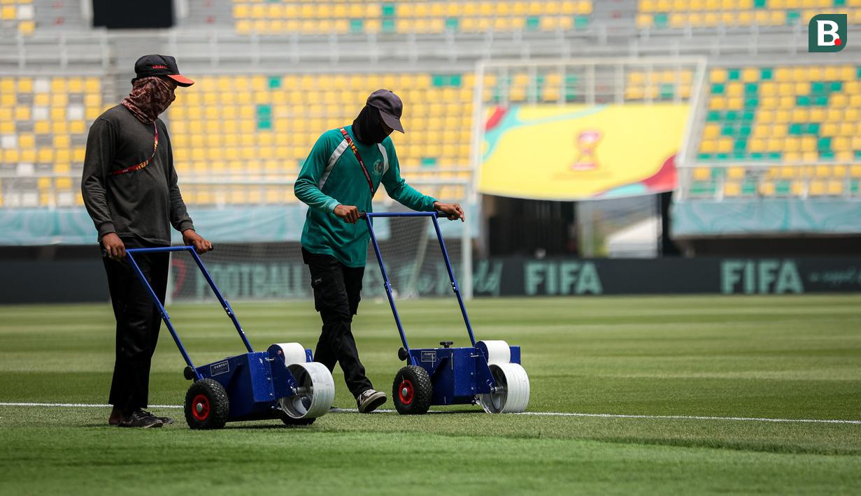 Dua orang pekerja tengah merapikan garis lapangan Stadion Gelora Bung Tomo (GBT) Surabaya, Jawa Timur, Kamis (9/11/2023) menjelang pembukaan Piala Dunia U-17 2023 yang akan diselenggarakan pada Jumat, 10 November 2023. (Bola.com/Bagaskara Lazuardi)