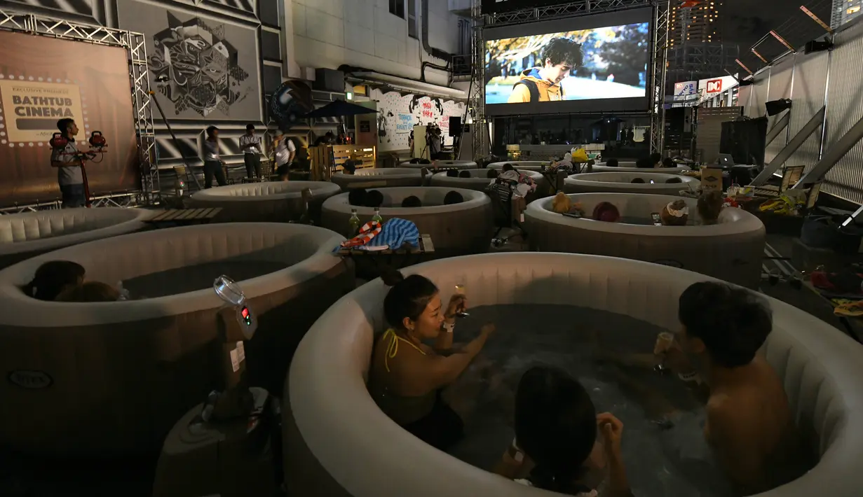 Pengunjung menikmati menonton film sambil berendam di Bathtub Cinema di atap gedung kawasan Shibuya, Tokyo, 17 Agustus 2018. Bagi para peminatnya harus merogoh kocek sebesar 18 ribu yen atau setara dengan Rp 2,3 juta per bathtub. (AFP/Kazuhiro NOGI)