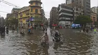 Orang-orang menyeberangi jalan yang banjir setelah hujan deras monsun di Karachi (25/7/2022). Keadaan darurat cuaca diumumkan di Karachi karena hujan muson yang lebih deras dari biasanya terus melanda kota terbesar di Pakistan, membanjiri rumah-rumah dan membuat jalan-jalan tidak dapat dilalui. (AFP/Asif Hassan)