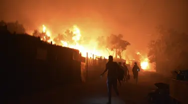 Pengungsi dan migran lari saat api membakar di kamp pengungsi Moria di timur laut pulau Aegean Lesbos, Yunani, Rabu (9/9/2020). Kamp tersebut digunakan sebagai tempat penampungan bagi para pengungsi dan imigran pencari suaka. (AP Photo/Panagiotis Balaskas)