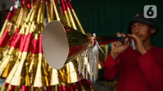 Pedagang sedang menjajal terompet buatannya di kawasan Glodok, Jakarta, Selasa (26/12/2023). (Liputan6.com/Faizal Fanani)