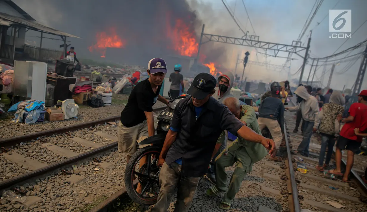 Warga bergotong royong menyelamatkan sepeda motor saat kebakaran ratusan rumah bedeng di permukiman liar belakang Hotel Alexis, Pademangan, Jakarta, Sabtu (16/9). Api semakin membesar akibat tiupan angin yang kencang. (Liputan6.com/Faizal Fanani)