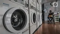 Pekerja duduk di bangku kasir saat menunggu pelanggan di Jaksa Clean Coin Laundry, Jalan Jaksa, Jakarta, Kamis (1/4/2021). Akibat pandemi Covid-19, jasa cuci pakaian mandiri atau self service mengalami sepi pelanggan mencapai 50 persen. (merdeka.com/Iqbal S Nugroho)