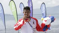Atlet modern pentathlon, Muhammad Taufik, menunjukan medali usai meraih perunggu pada nomor beach triathle individual SEA Games 2019 di Subic, Jumat (6/12). Dirinya membukukan catatan waktu 00:17:37.76.  (Bola.com/M Iqbal Ichsan)