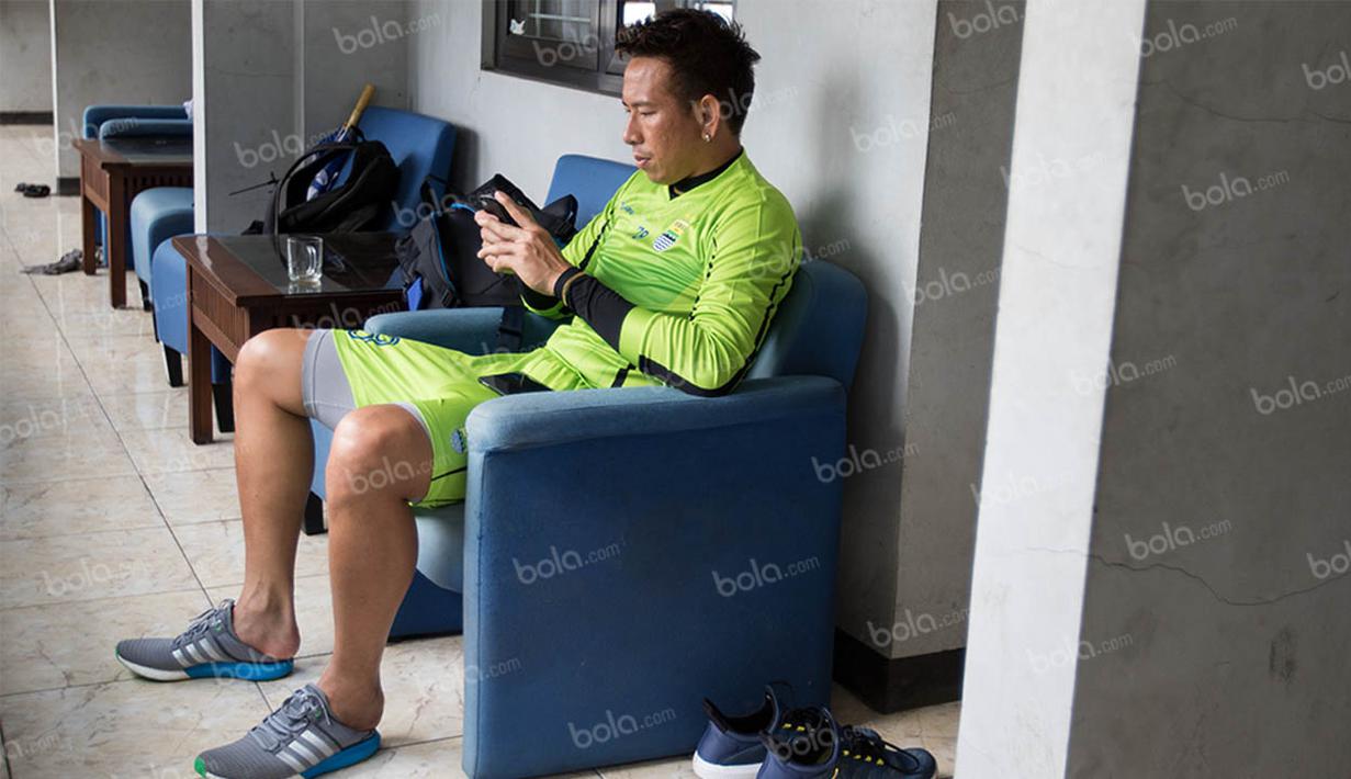 Kiper Persib, I Made Wirawan, asyik bermain ponsel ketika berada di Mess Persib Bandung, Jawa Barat, Senin (2/5/2016). (Bola.com/Vitalis Yogi Trisna)