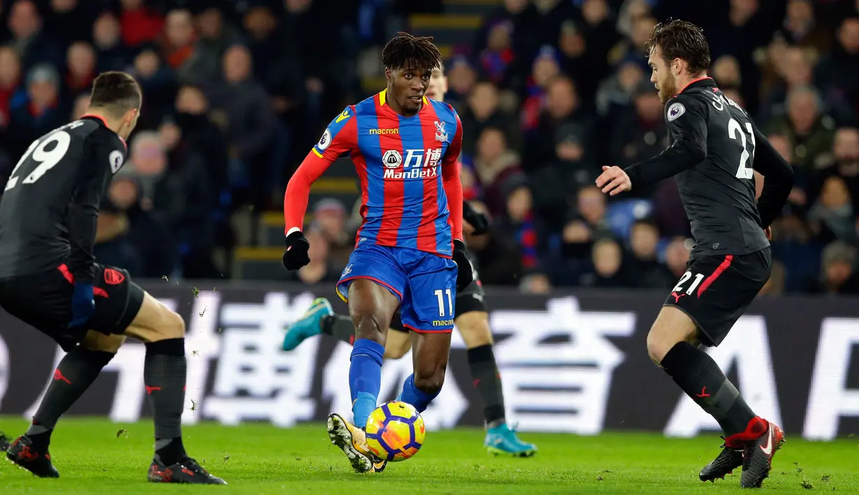 Pemain Crystal Palace Wilfried Zaha, berusaha melewati pemain Asrsenal saat pertandingan Liga Inggris di stadion Selhurst Park di London (28/12). Crystal Palace harus menelan kekalahan dikandang sendiri 2-3 atas Arsenal. (AP Photo/Alastair Grant)