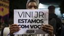 Seorang perempuan memegang tanda dengan pesan yang berbunyi dalam bahasa Portugis; "Vini, kami bersamamu," saat memprotes serangan rasis yang dialami pemain Real Madrid asal Brasil, Vinicius Jr., di luar Konsulat Spanyol di Sao Paulo, Brasil, Selasa (23/5/2023). (AP Photo/Tuane Fernandes)