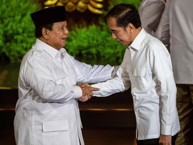 Presiden Republik Indonesia Prabowo Subianto (kiri), yang juga Ketua Umum Partai Gerakan Indonesia Raya (Gerindra), dan Presiden Republik Indonesia ke-7 Joko Widodo saling menyapa di atas panggung pada puncak perayaan ulang tahun ke-17 Partai Gerindra di Sentul International Convention Center (SICC), Bogor, Jawa Barat, Sabtu (15/2/2025). (ADITYA AJI/AFP)