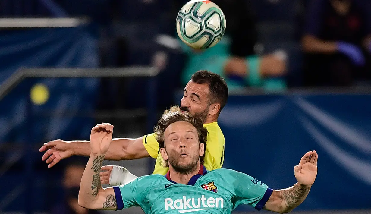 Gelandang Barcelona,Ivan Rakitic menyundul bola dengan dibayangi bek Villarreal, Mario Gaspar dalam pekan ke-34 La Liga Spanyol di stadion La Ceramica, Minggu (5/7/2020). Barcelona sukses menumbangkan tim tuan rumah Villarreal dengan skor telak 4-1. (JOSE JORDAN / AFP)