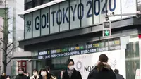 Orang-orang yang mengenakan masker berjalan dekat papan bertema Olimpiade yang disponsori perusahaan sekuritas di Tokyo, Jepang, Jumat (29/1/2021). Olimpiade 2020 Tokyo yang ditunda terkait pandemi virus corona Covid-19 dijadwalkan ulang untuk diadakan pada musim panas ini. (AP Photo/Hiro Komae)