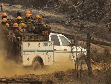 Petugas pemadam kebakaran Los Padres Hotshots naik ke lokasi baru untuk memotong jalur api di Oak Fire dekat Mariposa, California, Amerika Serikat, 26 Juli 2022. Petugas pemadam kebakaran membuat kemajuan dalam memerangi kebakaran hutan musim panas terbesar di California. (DAVID MCNEW/AFP)