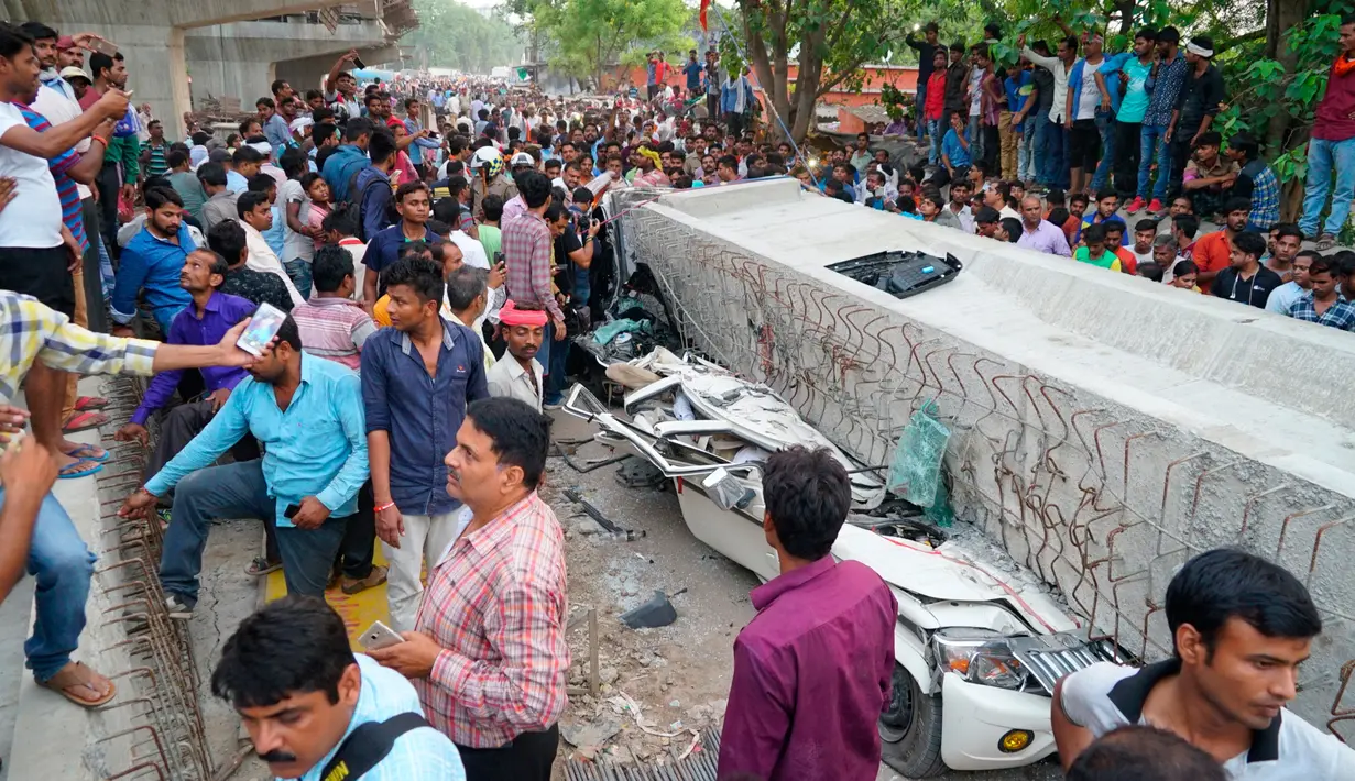 Warga India berkumpul untuk menyaksikan lokasi runtuhnya material jalan layang di kota Varanasi, Selasa (15/5). Sedikitnya 18 orang tewas dan belasan orang terperangkap setelah jembatan layang roboh dan menghancurkan kendaraan di bawahnya. (AP Photo)