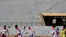 Pemain sepak bola tim lokal Suriah bertanding dengan latar belakang tembok yang rusak bekas terkena peluru di stadion Raqqa yang dulunya ibu kota Suriah (16/4). (AFP/Delil Souleiman)