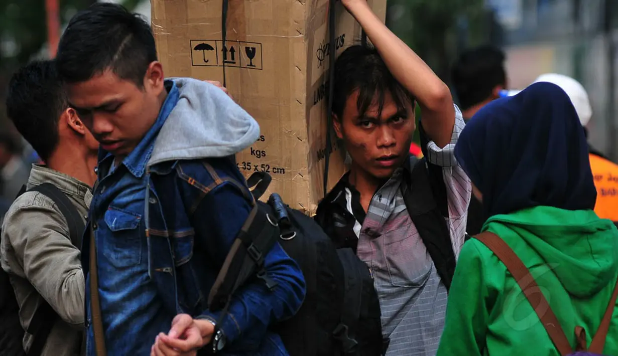 Seorang calon pemudik tampak memanggul kardus besar di terminal Grogol, Jakarta, Senin (21/7/14. (Liputan6.com/Johan Tallo) 