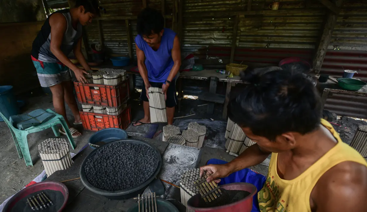 Para pekerja menyelesaikan pembuatan petasan di sebuah pabrik di Bocaue, Bulacan, Filipina, Jumat (27/12/2019). Petasan-petasan tersebut akan dijual untuk perayaan Tahun Baru 2020. (Maria TAN/AFP)