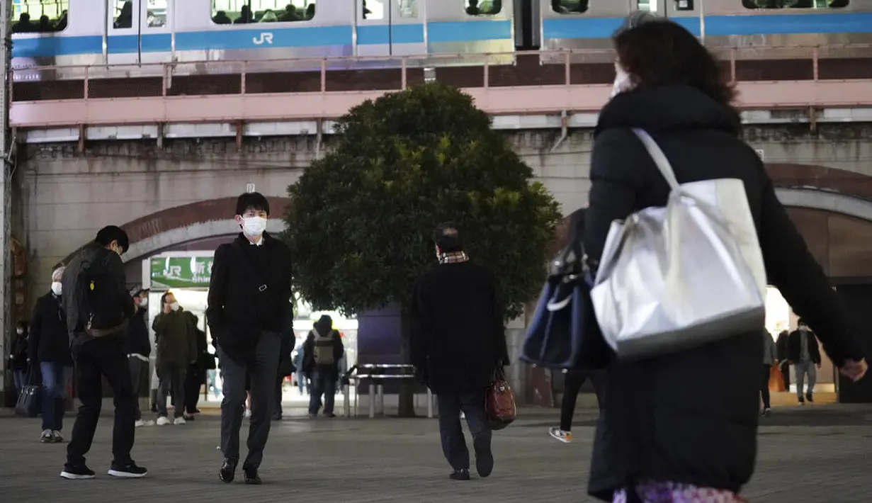 Orang-orang yang mengenakan masker untuk mengekang penyebaran virus corona COVID-19 berjalan di luar stasiun kereta di Tokyo, Jepang, Rabu (6/1/2021). Ibu kota Jepang itu mengkonfirmasi lebih dari 1.500 kasus baru virus corona COVID-19 pada 6 Januari 2021. (AP Photo/Eugene Hoshiko)