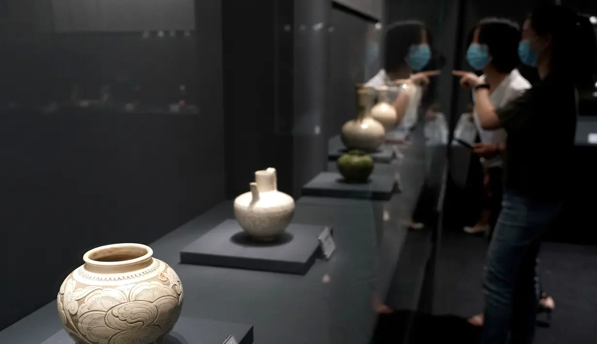 Pengunjung mengamati benda yang dipajang dalam pameran keramik di Zhengzhou, Provinsi Henan, China, 25 Agustus 2020. Pameran keramik tersebut dimulai di Zhengzhou pada Selasa (25/8) dengan menampilkan 100 lebih benda dari zaman kuno yang ditemukan di sepanjang cekungan Sungai Kuning. (Xinhua/Li An)