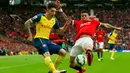 Bek Arsenal, Héctor Bellerín (kiri) berusaha mengumpan bola dari kejaran bek Marcos Rojo saat Laga Liga Premier Inggris di Stadion Old Trafford, Minggu (17/5/2015). Manchester United bermain imbang 1-1 atas Arsenal. (Reuters/Jason Cairnduff)