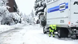 Seorang pengemudi truk Penske menunggu kedatangan rantai ban pada Senin pagi di sepanjang jalan layang Broad Street, di Nevada City, California (27/12/2021). Banyak warga yang tidak mendapatkan listrik atau terjebak di salju. (Elias Funez/The Union via AP)