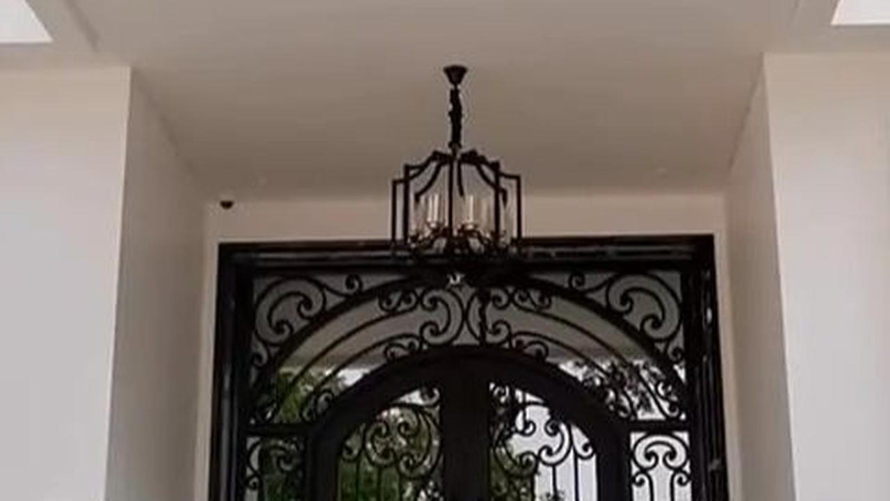 Rumah ini dua lantai, pintu masuk estetik dengan kaca satu arah dan model teralis hitam yang elegan.