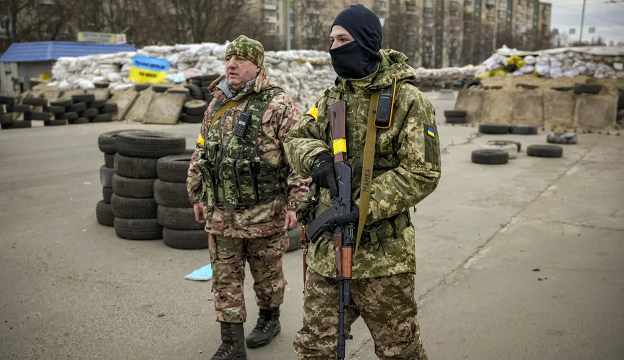 Seorang prajurit Ukraina memiliki tulisan "Mommy" pada tali senjatanya saat dia berjaga di sebuah pos pemeriksaan di jalan utama di Kyiv, Ukraina, 7 Maret 2022. (AP Photo/Vadim Ghirda)
