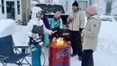 Sekelompok tetangga berkumpul di sekitar api unggun setelah membersihkan salju di Culver Road, Buffalo, New York, Amerika Serikat, 26 Desember 2022. Sebelumnya dilaporkan sebagian besar korban tewas berpusat di dalam dan sekitar Buffalo. (AP Photo/Carolyn Thompson)