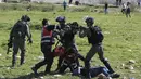 Petugas medis Palestina mengobati demonstran yang terlibat bentrokan saat tentara Israel menodongkan senjata ke rekannya di Ramallah, Tepi Barat, Senin (12/3). Aksi protes terkait pengangkapan salah satu mahasiswa oleh pasukan Israel. (ABBAS MOMANI/AFP)
