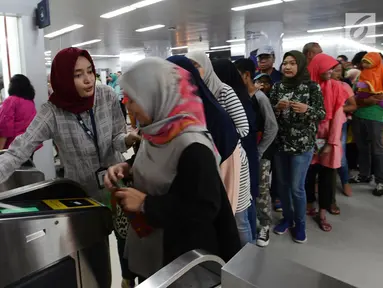 Petugas membantu calon penumpang melakukan tap kartu saat akan menggunakan layanan transportasi Moda Raya Terpadu (MRT) di Stasiun Bundaran HI, Jakarta, Rabu (3/4). Meski sudah tidak digratiskan, warga tetap antusias menjajal MRT. (merdeka.com/Imam Buhori)
