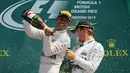 Pembalap Formula 1, Lewis Hamilton (kiri) menyemprotkan sampanye ke teman satu timnya, Nico Rosberg usai berlaga di Grand Prix Formula 1 Silverstone di Inggris, (5/7/2015). (Reuters/Paul Childs)