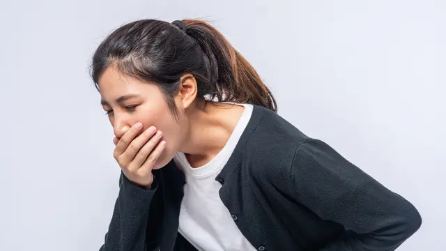 Seseorang sedang Memegang Perut dan Mual