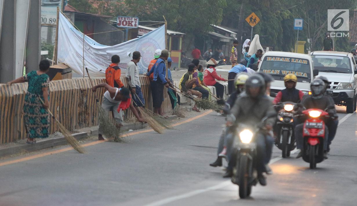 Warga membawa sapu menunggu pengguna jalan memberi sedekah dengan melempar uang di Jembatan Sewo, Jalur Pantura Sukra Indramayu, Jawa Barat, Senin (3/6/2019). Keberadaan pencari sedekah bisa membahayakan keselamatan pemudik serta pengguna jalan lainnya. (Liputan6.com/Herman Zakharia)