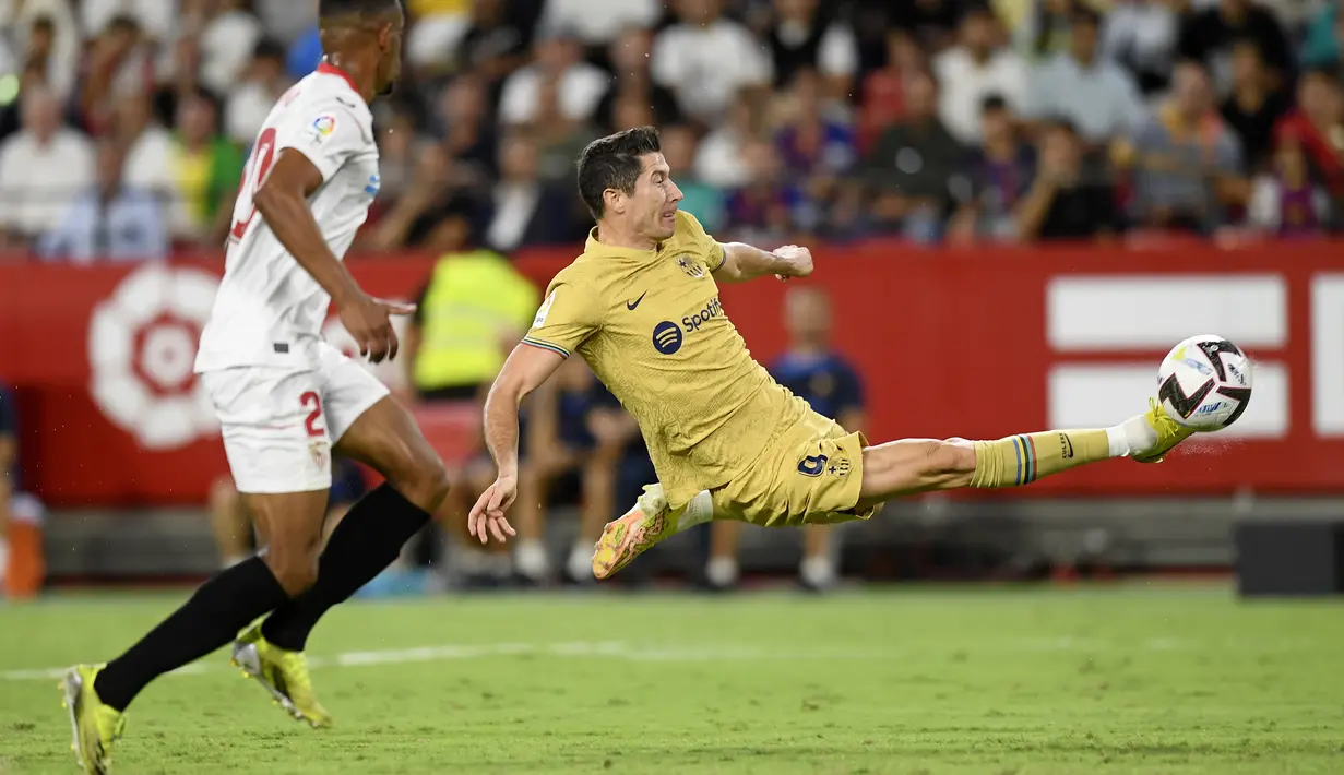 Penyerang Barcelona, Robert Lewandowski mencoba melepaskan tembakan saat bertanding melawan Sevilla pada pertandingan lanjutan La Liga Spanyol di Seville, Spanyol, Sabtu (3/9/2022). Barcelona menang telak atas Sevilla 3-0. (AP Photo/Jose Breton)