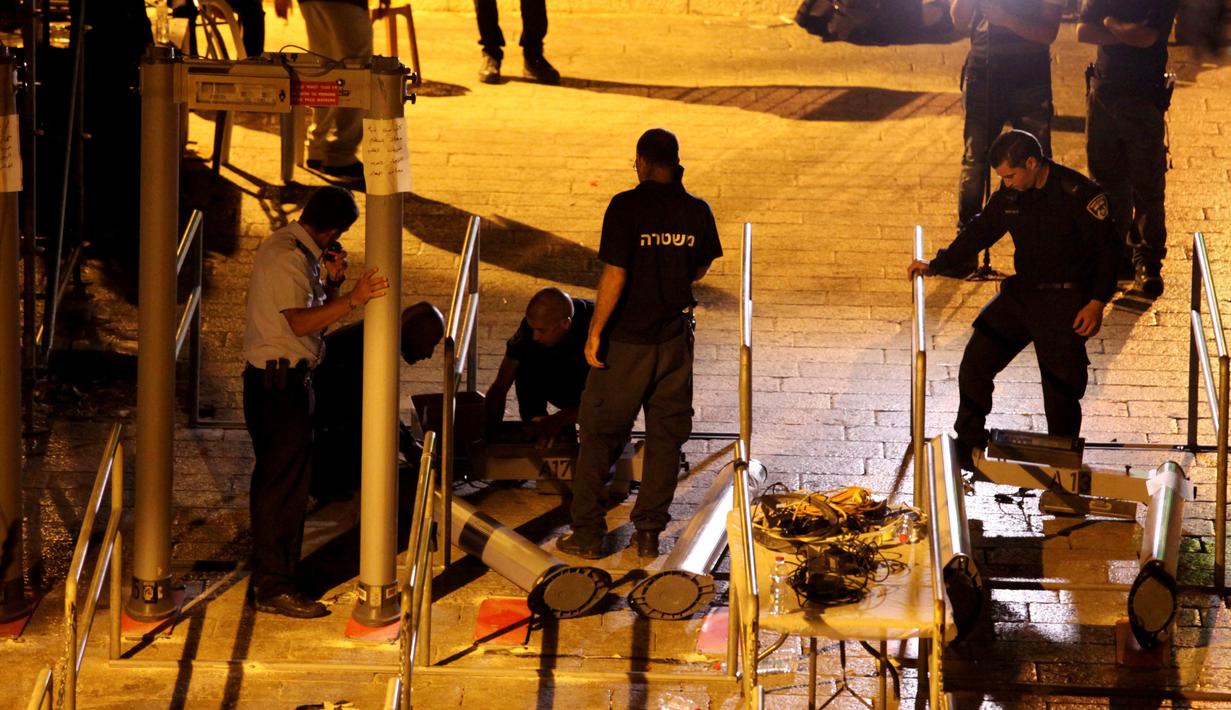 Polisi Israel menyingkirkan detektor logam di depan pintu masuk kompleks Masjid Al Aqsa di Kota Tua Yerusalem, Selasa (25/7) dini hari. Ketegangan menyebar cepat sejak Israel memasang detektor logam di pintu masuk area tersebut. (AP Photo/Mahmoud Illean)