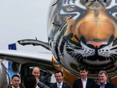 Pengunjung berpose di depan pesawat Embraer E190-E2 yang dipamerkan pada ajang Singapore Airshow 2018 di Changi, Singapura, (7/2). Embraer memamerkan secara perdana pesawat E190-E2 dengan design harimau dibagian kepala. (AP Photo / Yong Teck Lim)