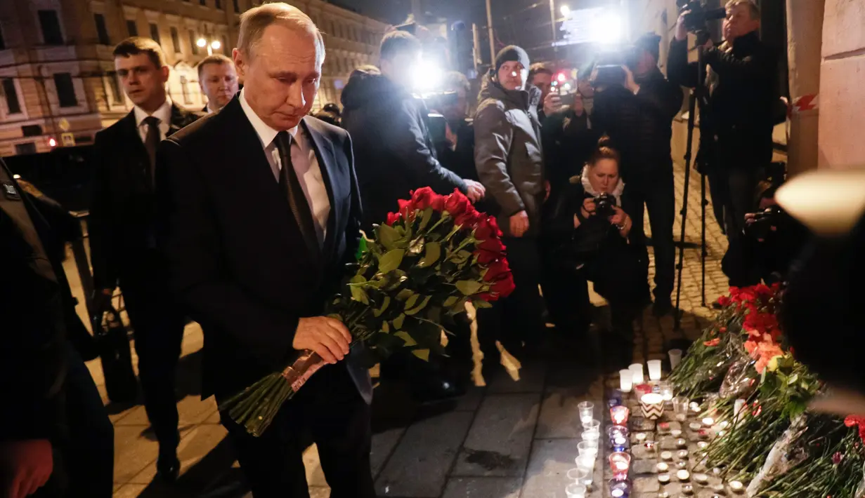 Presiden Rusia, Vladimir Putin membawa karangan bunga di dekat lokasi ledakan bom di stasiun kereta bawah tanah di St. Petersburg, Senin (3/4). Putin memberi penghormatan kepada para korban ledakan yang terjadi di lokasi itu. (AP Photo/Dmitri Lovetsky)