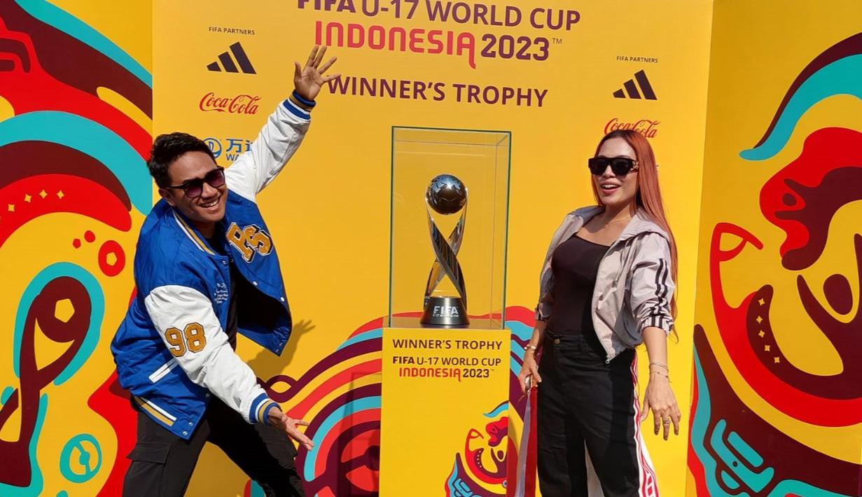 Musisi Ridwan Naibaho (kiri) dan Lilis Darawangi berpose bersama trofi Piala Dunia u-17 2023 alam acara Trophy Experience yang berlangsung di Balai Pemuda Surabaya, Minggu (29/10/2023). (Dok. SCM)