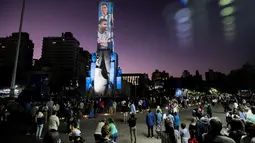 Video mapping memperlihatkan gambar bintang sepak bola Argentina Lionel Messi dan Angel Di Maria di "Monumento Nacional a la Bandera" di Rosario, Senin (21/11/2022). Proyeksi cahaya tersebut sebagai bentuk untuk menyemangati timnas Argentina sebelum menghadapi Arab Saudi dalam laga pertama Grup C Piala Dunia 2022, Selasa (22/11/2022) petang WIB. (Marcelo Manera / AFP)