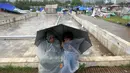 Para pengunjuk rasa anti Perdana Menteri Nawaz Sharif berlindung dari terpaan hujan saat melakukan aksi di sekitar gedung Parlemen Pakistan, (4/9/2014). (REUTERS/Akhtar Soomro)