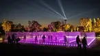 Pengunjung berjalan di dalam pertunjukan cahaya dan air mancur yang ditampilkan menjelang perayaan Natal di Experience Park, di distrik pesisir Hellenikon di Athena, Senin (20/12/2021).  (AFP/Angelos Tzortzinis)