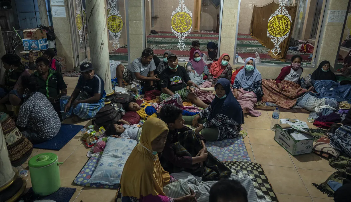 Pengungsi berlindung pasca erupsi Gunung Semeru di Masjid Desa Sumber Wuluh, Lumajang (5/12/2021). Warga pun diimbau menjauhi daerah sekitar sungai yang berhulu di Gunung Semeru. (AFP/Juni Kriswanto)