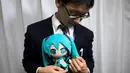 Akihiko Kondo asal Jepang berpose dengan boneka aktris virtual, Hatsune Miku sambil mengenakan cincin kawin mereka di Tokyo, 10 November 2018. Pria berusia 35 tahun itu memutuskan menikah dengan boneka anime pada 4 November lalu. (Behrouz MEHRI/AFP)